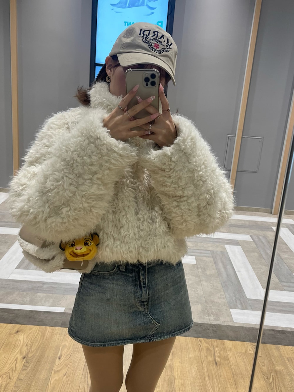 ホワイト系のブルゾン、ベージュ系のショルダーバッグ、ブルー系のデニムスカートを着用したレディースの夏コーディネートの4枚目の写真