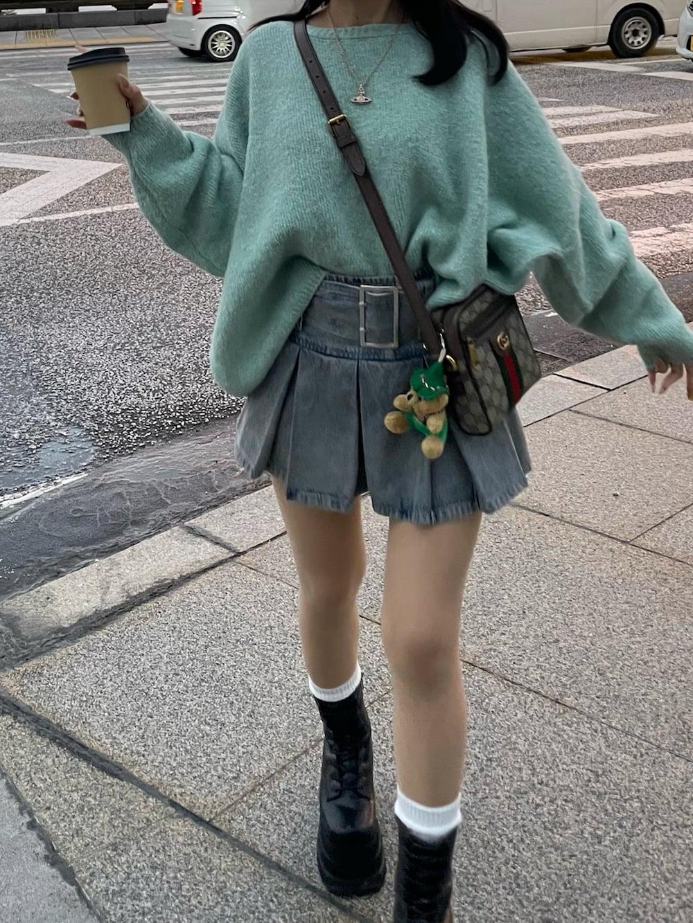 グリーン系のニット/セーター、ブルー系のデニムスカート、ブラック系のブーツを着用したレディースの秋コーディネートの5枚目の写真