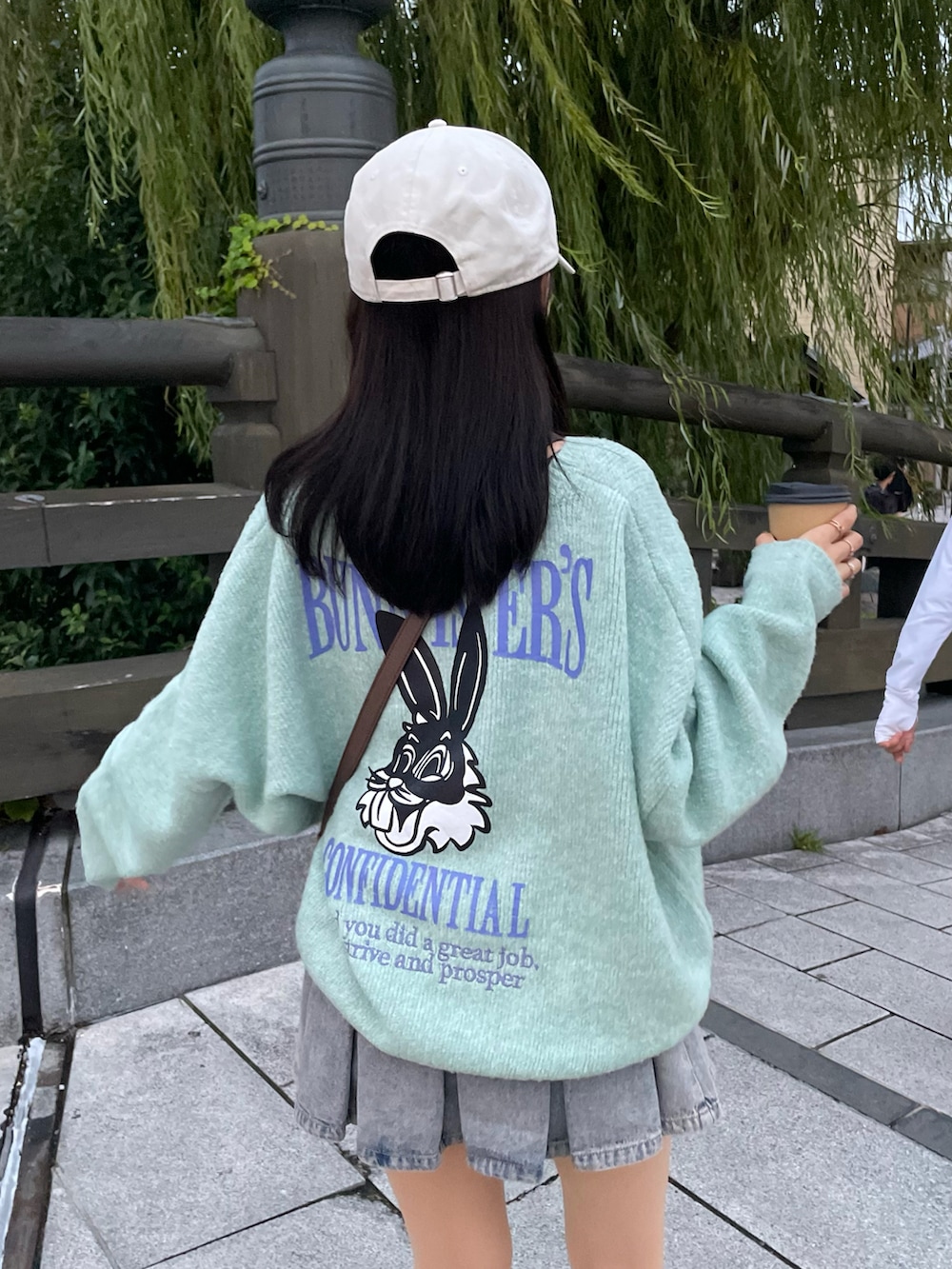 グリーン系のニット/セーター、ブルー系のデニムスカート、ブラック系のブーツを着用したレディースの秋コーディネートの4枚目の写真