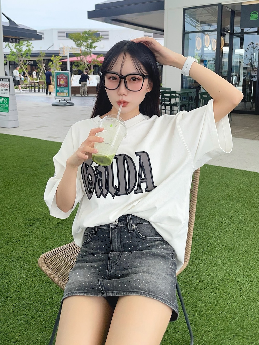 ホワイト系のTシャツ/カットソー、ブラック系のデニムスカート、ブラック系のサンダルを着用したレディースの夏コーディネートの2枚目の写真