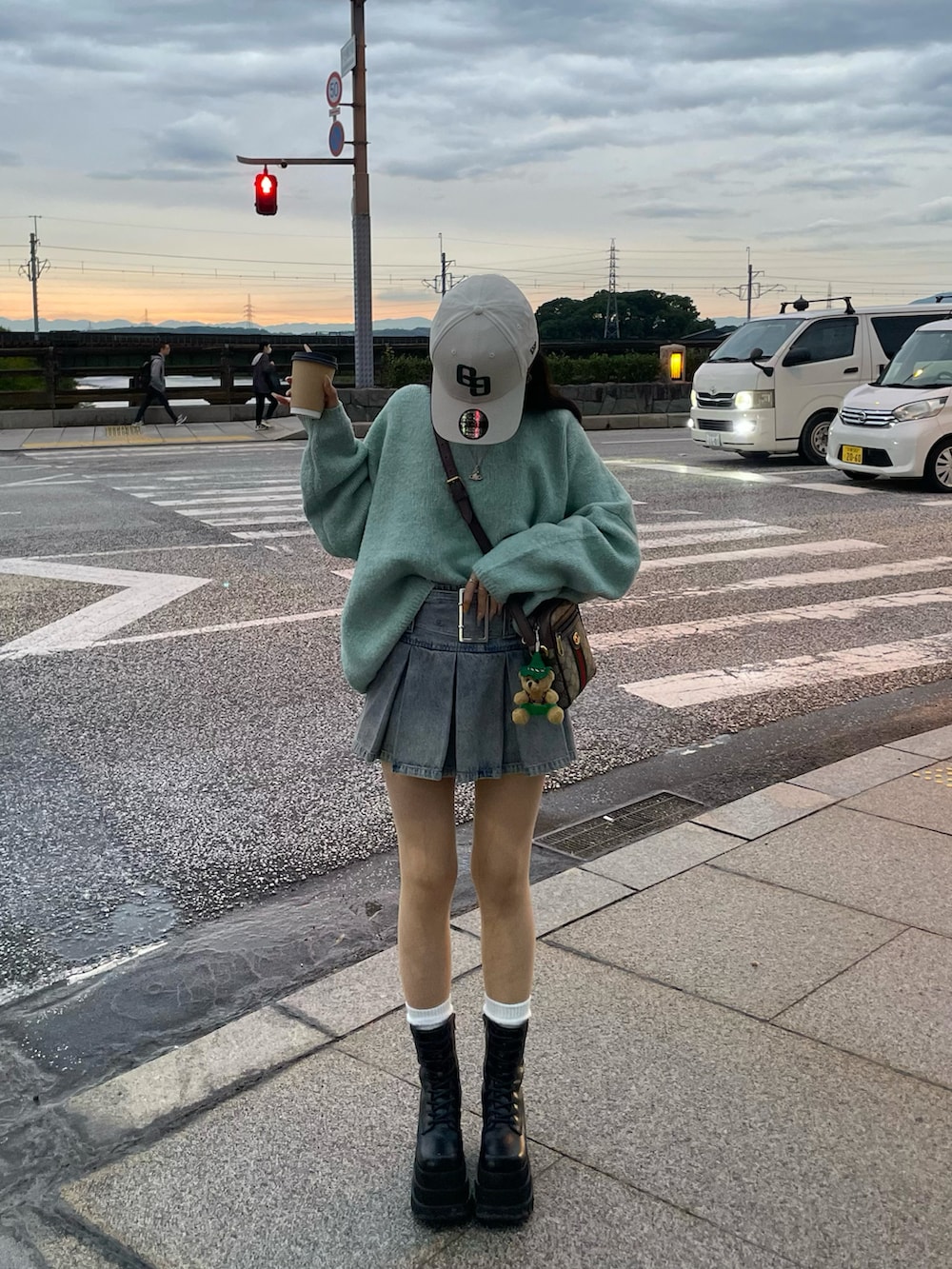 グリーン系のニット/セーター、ブルー系のデニムスカート、ブラック系のブーツを着用したレディースの秋コーディネートの2枚目の写真