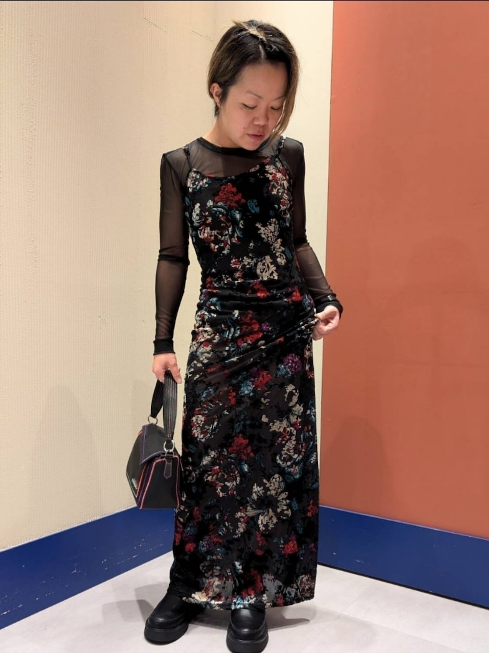 ブラック系のワンピース、ブラック系のブーツ、ブラック系のハンドバッグを着用したレディースの秋コーディネートの3枚目の写真