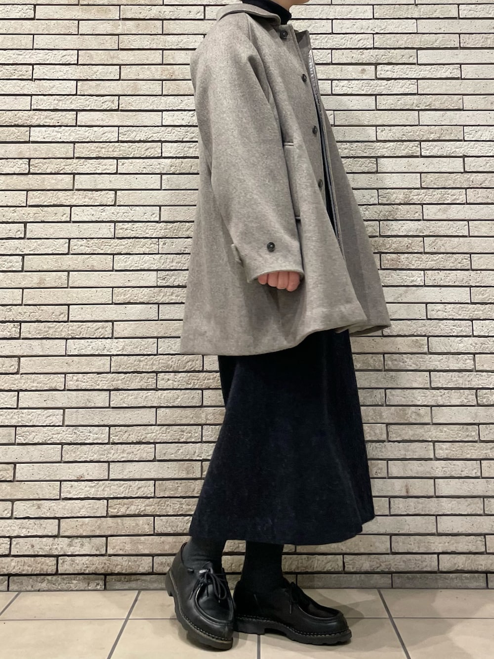 グレー系のステンカラーコート、グレー系のワンピースを着用したレディースの秋コーディネートの3枚目の写真