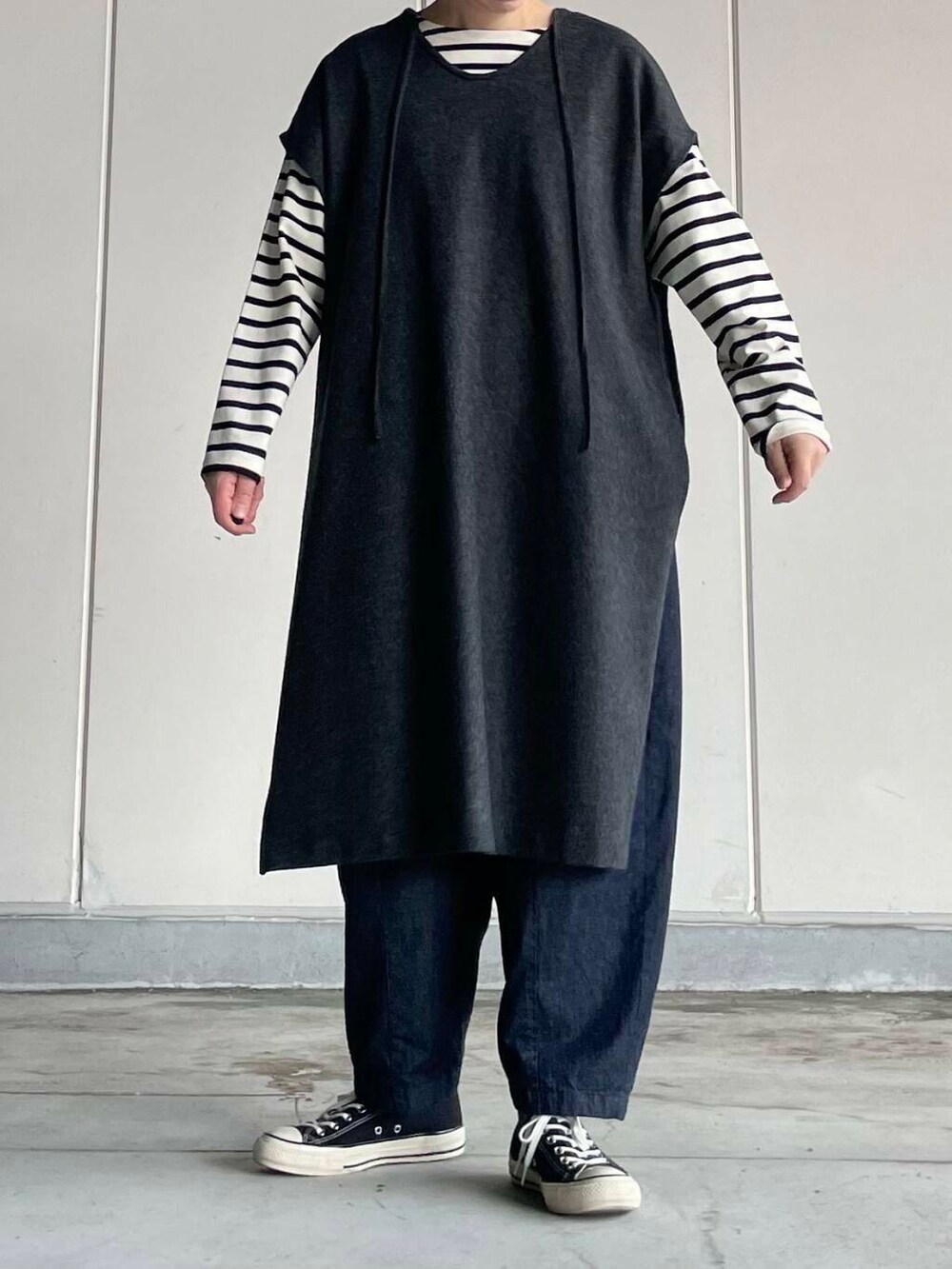 ブルー系のデニムパンツ、ホワイト系のTシャツ/カットソー、グレー系のワンピースを着用したレディースの秋コーディネートの2枚目の写真