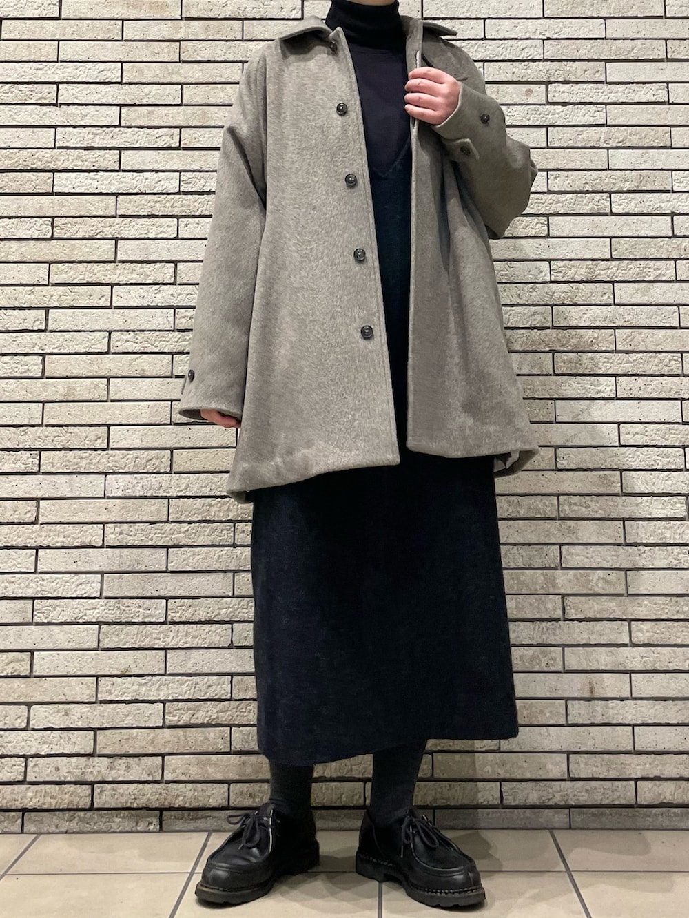 グレー系のステンカラーコート、グレー系のワンピースを着用したレディースの秋コーディネートの2枚目の写真