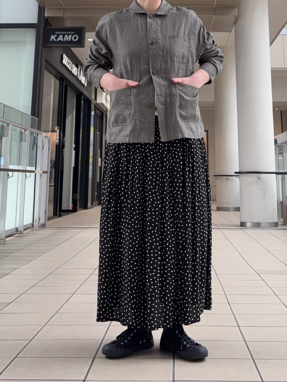 グレー系のカバーオール、ブラック系のスカートを着用したレディースの春コーディネートの4枚目の写真