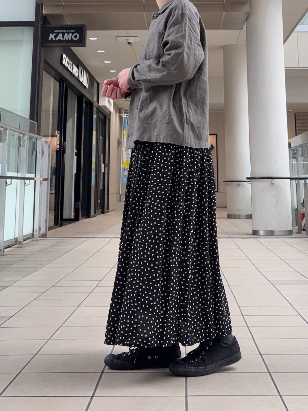 グレー系のカバーオール、ブラック系のスカートを着用したレディースの春コーディネートの3枚目の写真