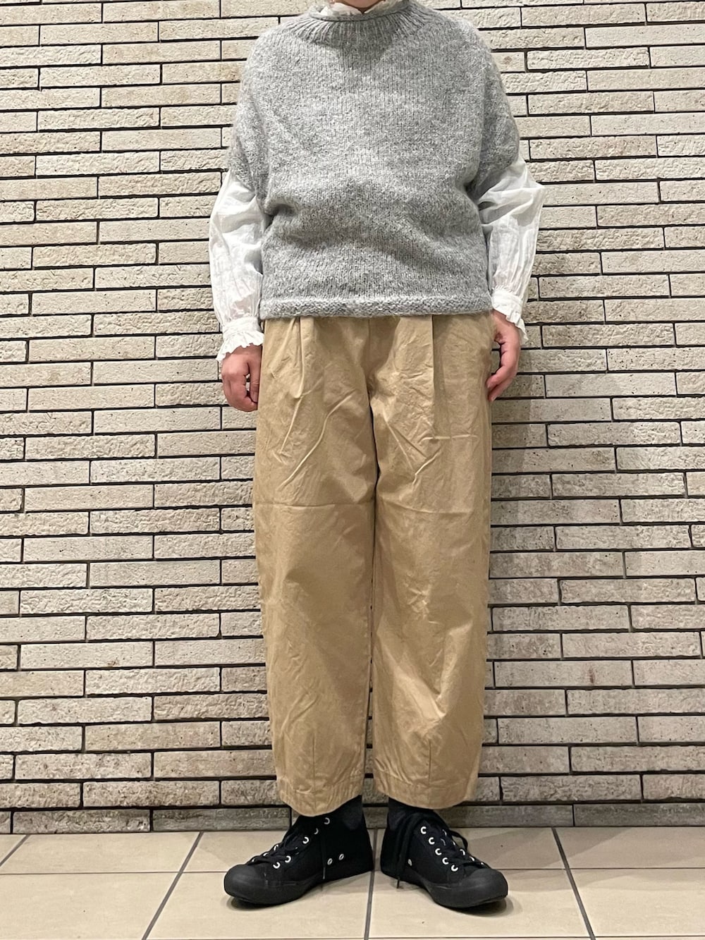 グレー系のニット/セーター、ベージュ系のその他パンツ、ホワイト系のシャツ/ブラウスを着用したレディースの秋コーディネートの2枚目の写真