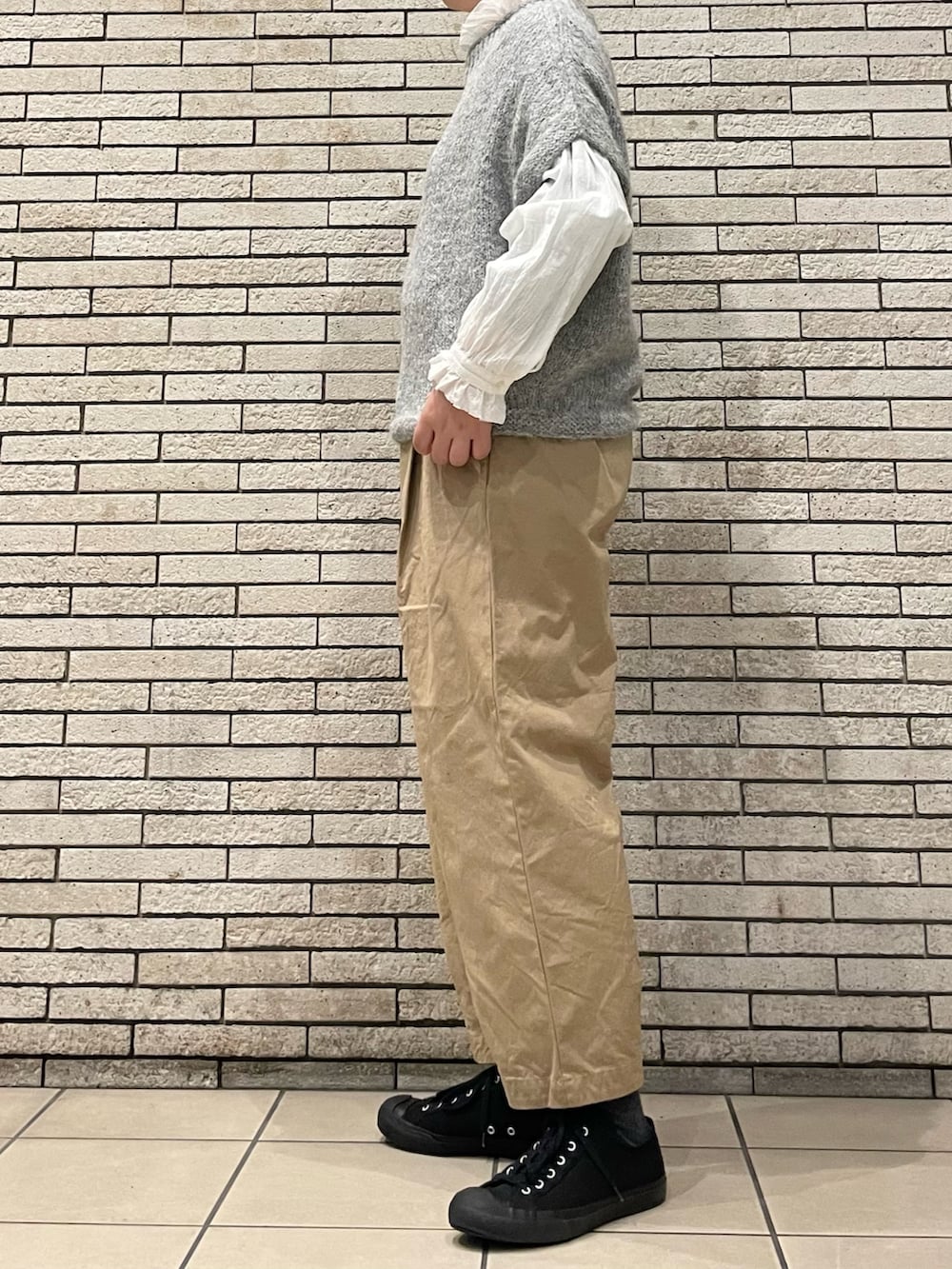 グレー系のニット/セーター、ベージュ系のその他パンツ、ホワイト系のシャツ/ブラウスを着用したレディースの秋コーディネートの3枚目の写真