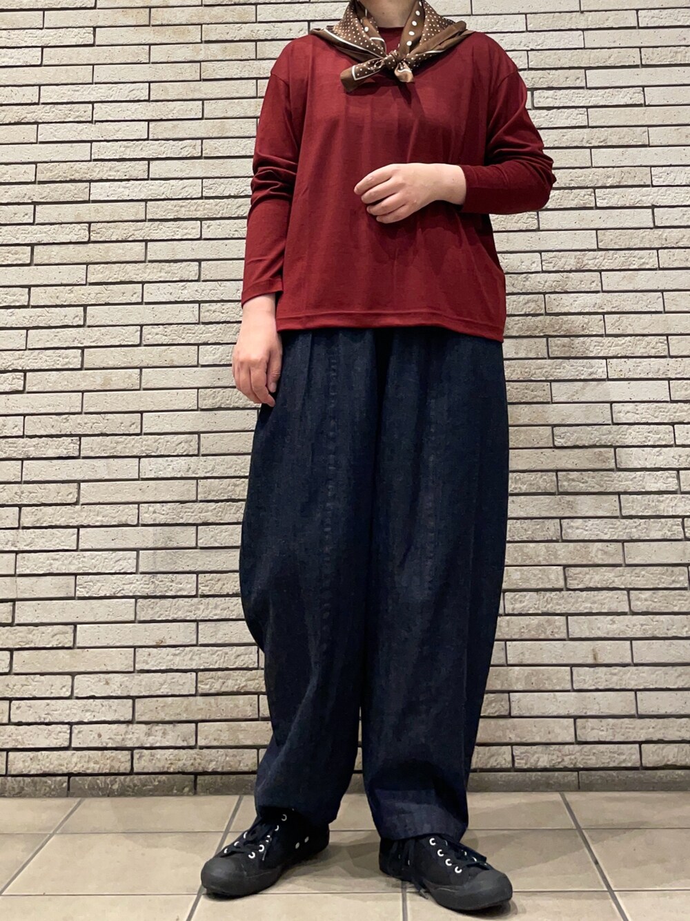 レッド系のTシャツ/カットソー、ブルー系のデニムパンツを着用したレディースの秋コーディネートの2枚目の写真