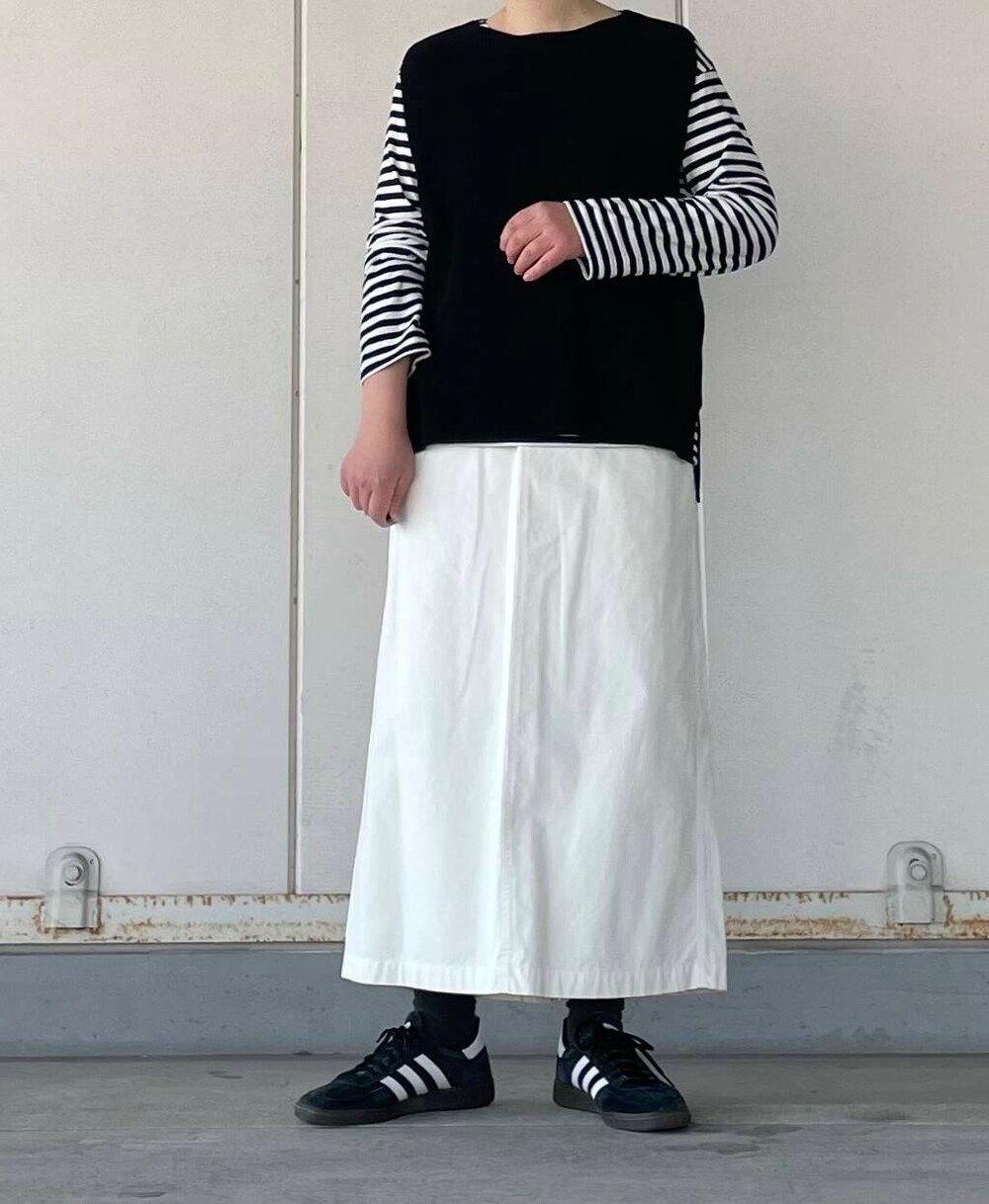 ホワイト系のスカート、ブラック系のベストを着用したレディースの冬コーディネートの2枚目の写真