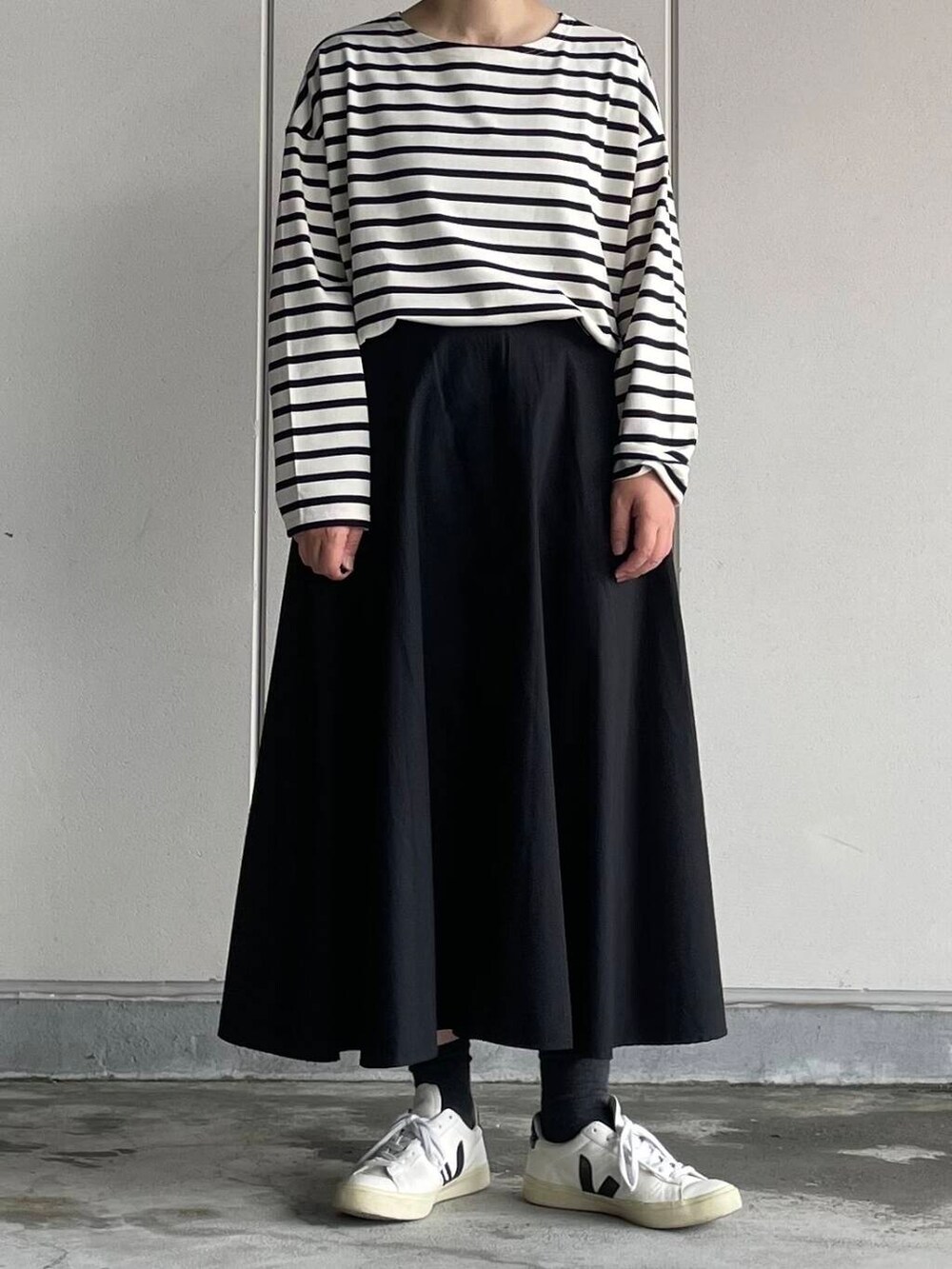 ブラック系のスカート、ホワイト系のTシャツ/カットソーを着用したレディースの秋コーディネートの2枚目の写真