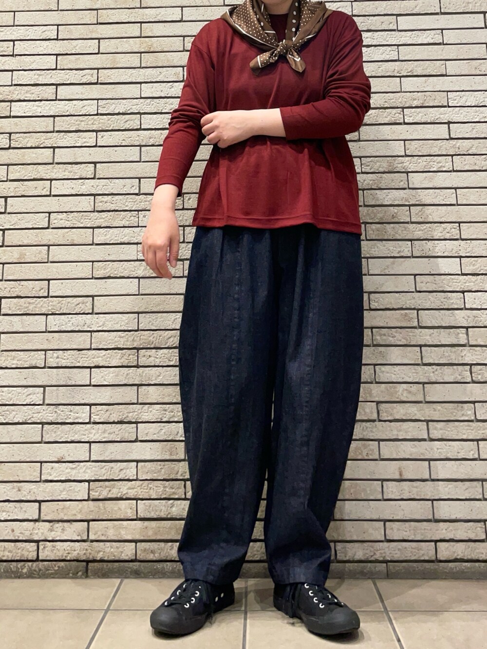 レッド系のTシャツ/カットソー、ブルー系のデニムパンツを着用したレディースの秋コーディネートの3枚目の写真