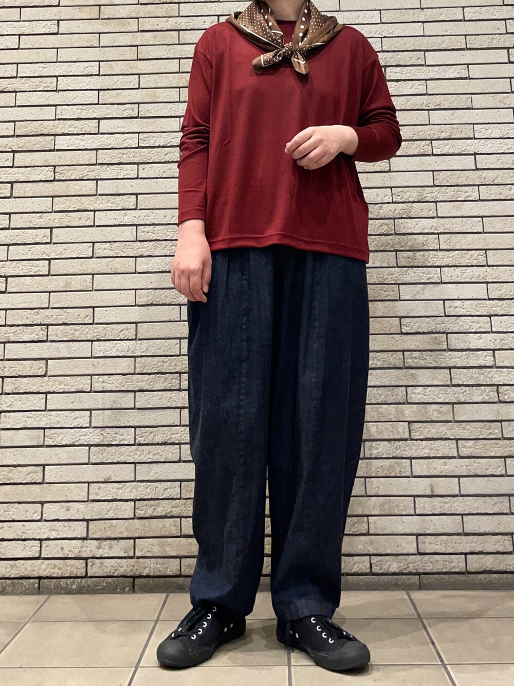 レッド系のTシャツ/カットソー、ブルー系のデニムパンツを着用したレディースの秋コーディネートの4枚目の写真