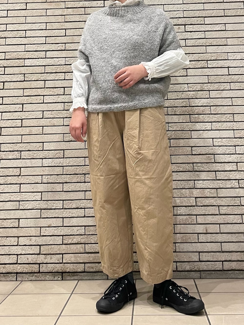 グレー系のニット/セーター、ベージュ系のその他パンツ、ホワイト系のシャツ/ブラウスを着用したレディースの秋コーディネートの4枚目の写真