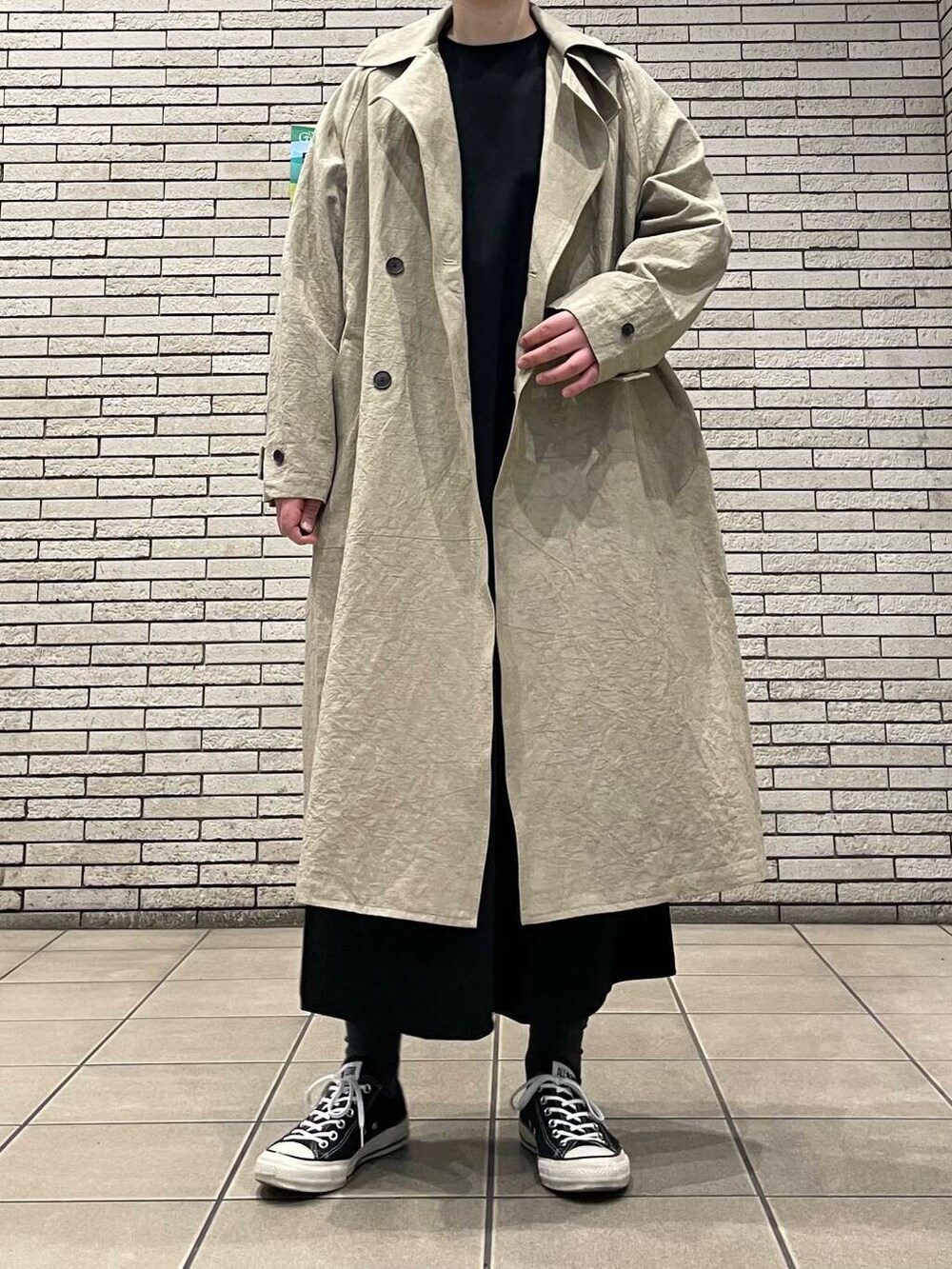 ベージュ系のトレンチコートを着用したレディースの春コーディネートの2枚目の写真