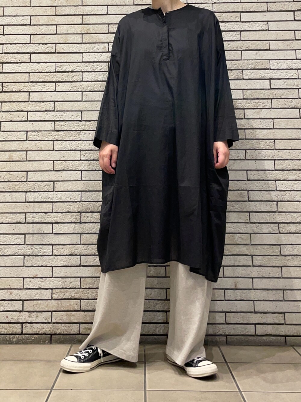 ブラック系のチュニック、ベージュ系のその他パンツを着用したレディースの夏コーディネートの2枚目の写真