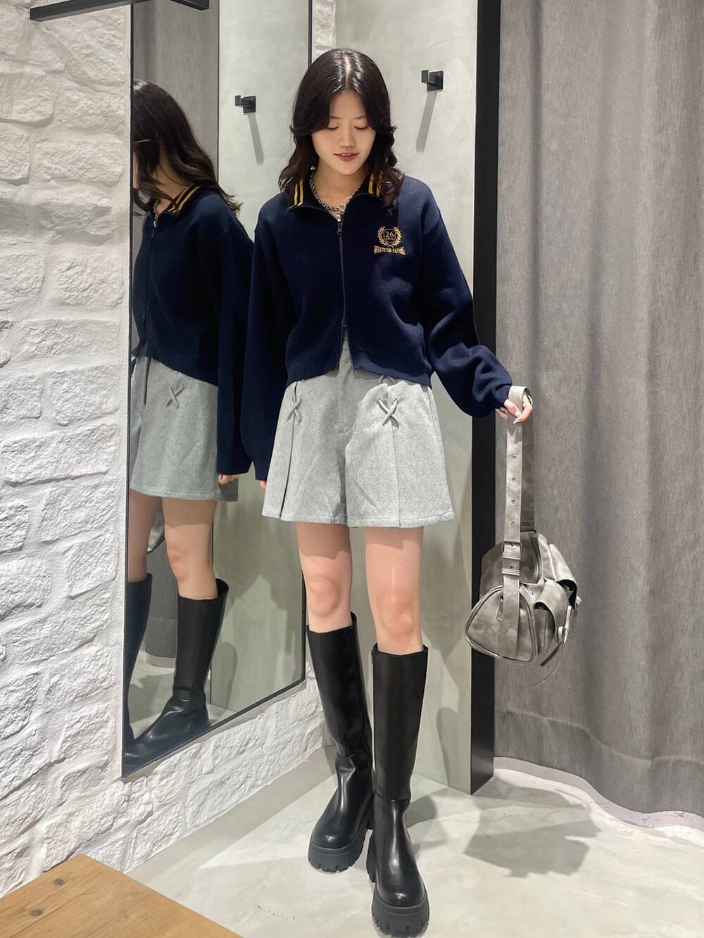 グレー系のショルダーバッグ、ブラック系のその他パンツ、ブラック系のブーツを着用したレディースの秋コーディネートの2枚目の写真