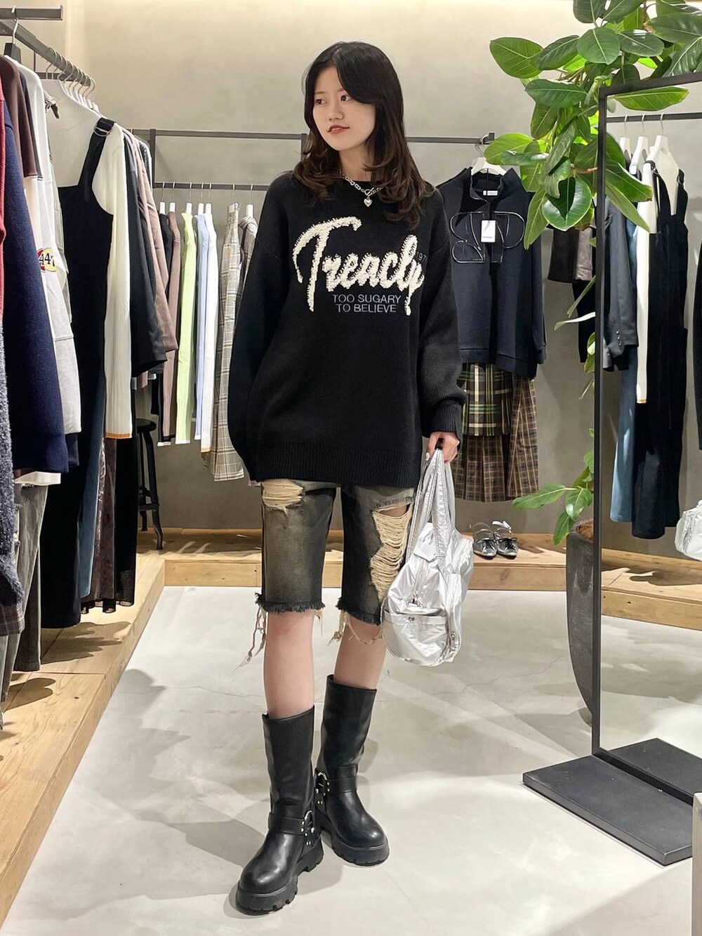 シルバー系のショルダーバッグ、ブラック系のニット/セーター、ブラック系のデニムパンツを着用したレディースの秋コーディネートの3枚目の写真