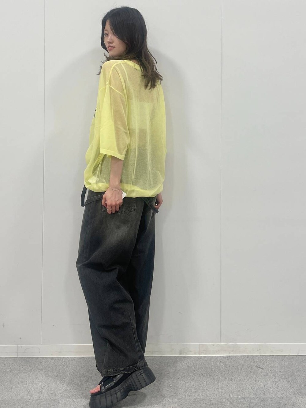 ブラック系のスニーカー、ブラック系のデニムパンツ、イエロー系のTシャツ/カットソーを着用したレディースの夏コーディネートの3枚目の写真