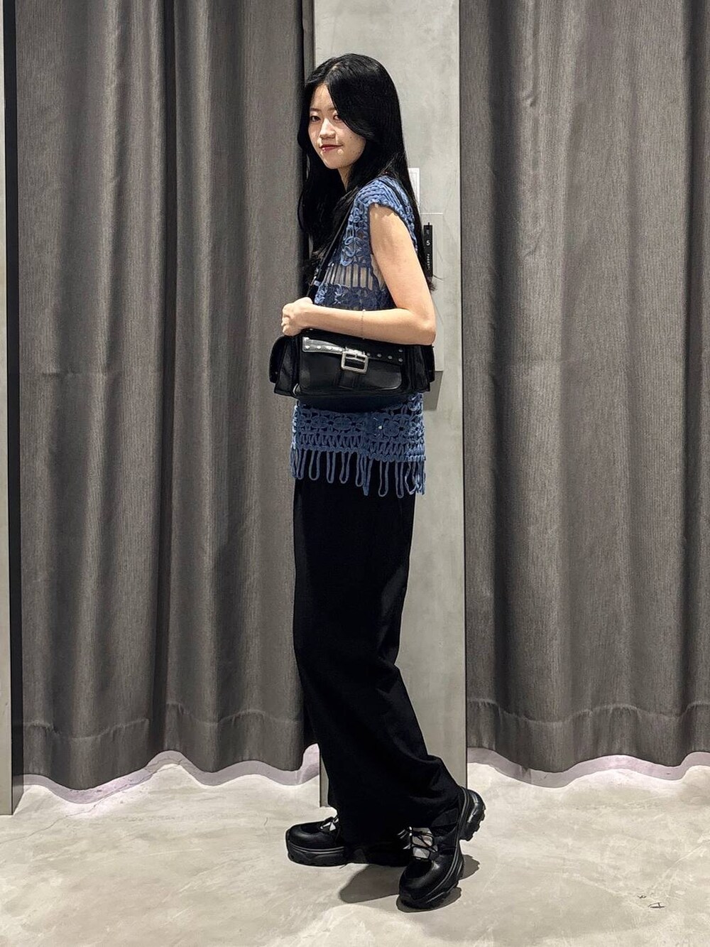 ホワイト系のタンクトップ、ブラック系のスラックス、ブルー系のベストを着用したレディースの夏コーディネートの3枚目の写真