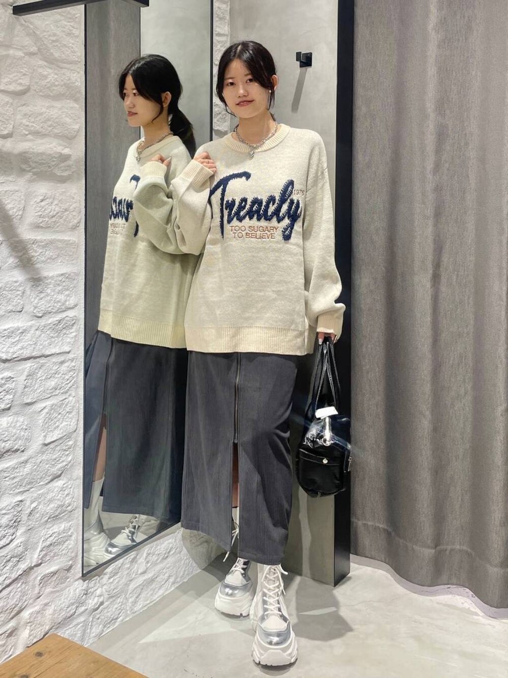 ホワイト系のブーツ、グレー系のスカート、ホワイト系のニット/セーターを着用したレディースの冬コーディネートの2枚目の写真