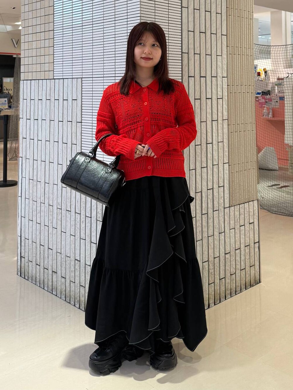 ブラック系のスニーカー、ブラック系のスカート、ブラック系のボストンバッグを着用したレディースの春コーディネートの4枚目の写真