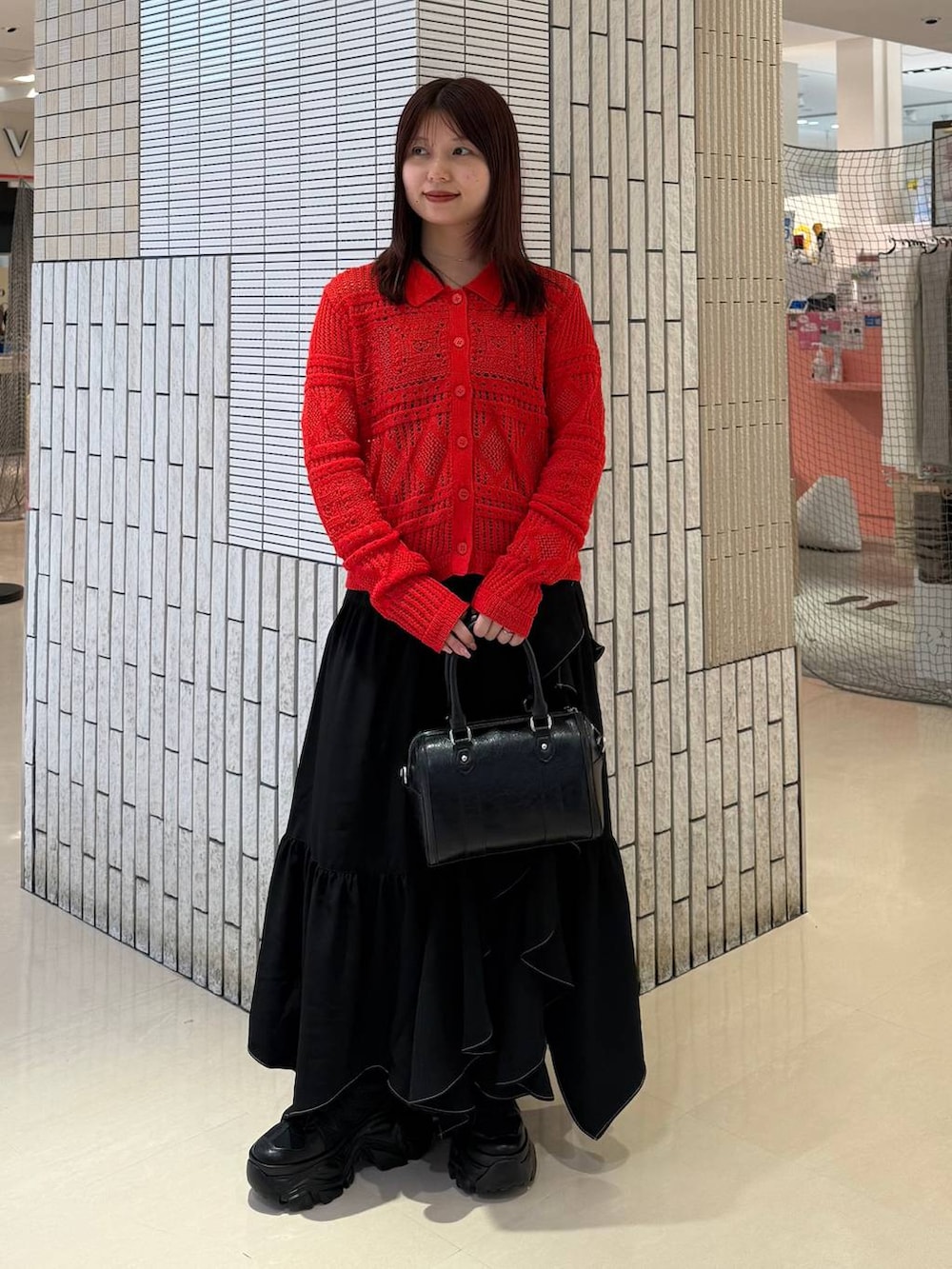 ブラック系のスニーカー、ブラック系のスカート、ブラック系のボストンバッグを着用したレディースの春コーディネートの2枚目の写真