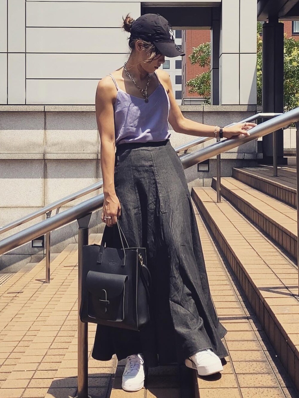 ブラック系のデニムスカート、ホワイト系のキャップを着用したレディースの夏コーディネートの2枚目の写真