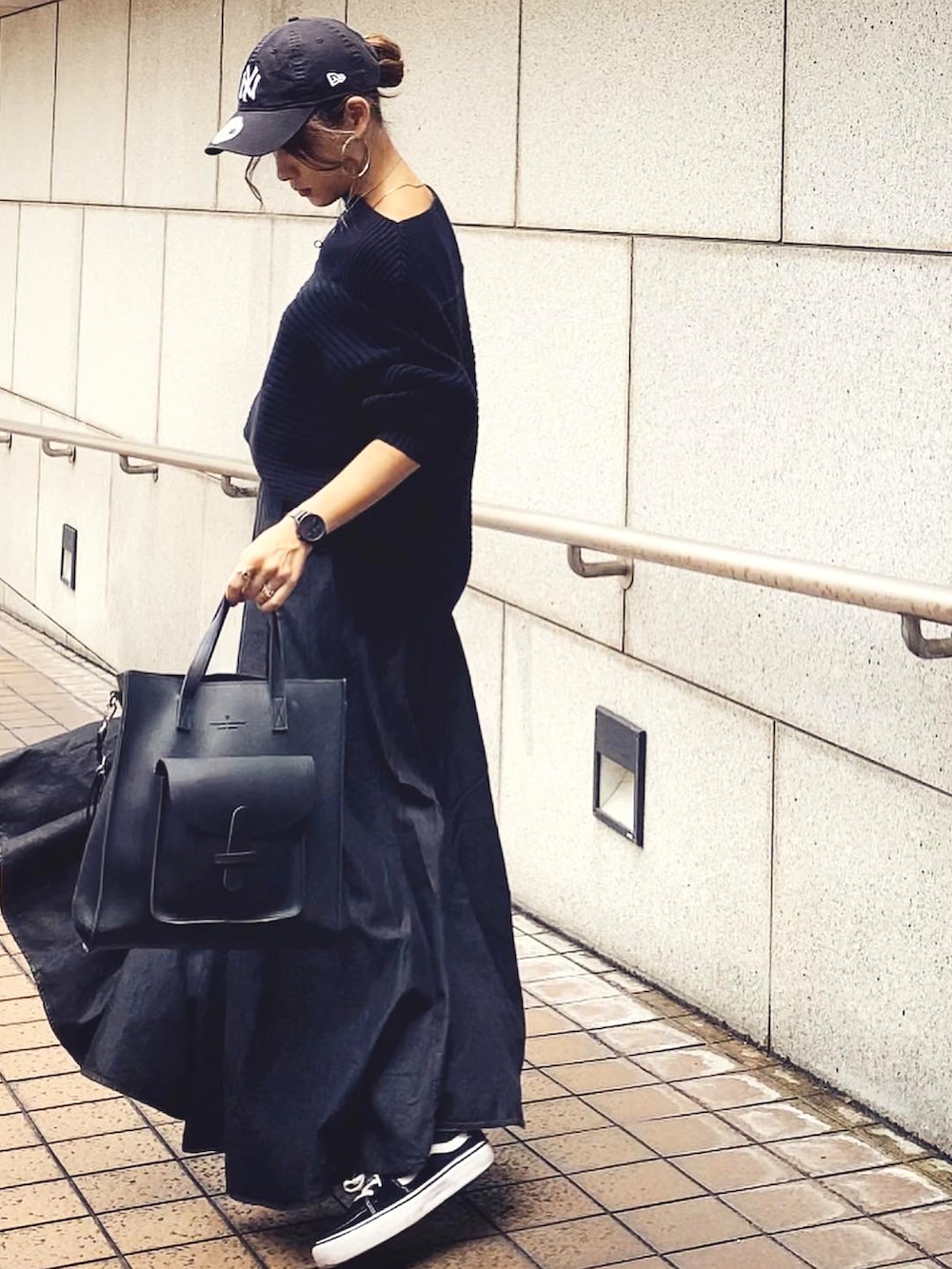 ブラック系のデニムスカート、ホワイト系のキャップ、ブラック系のアナログ腕時計を着用したレディースの秋コーディネートの2枚目の写真