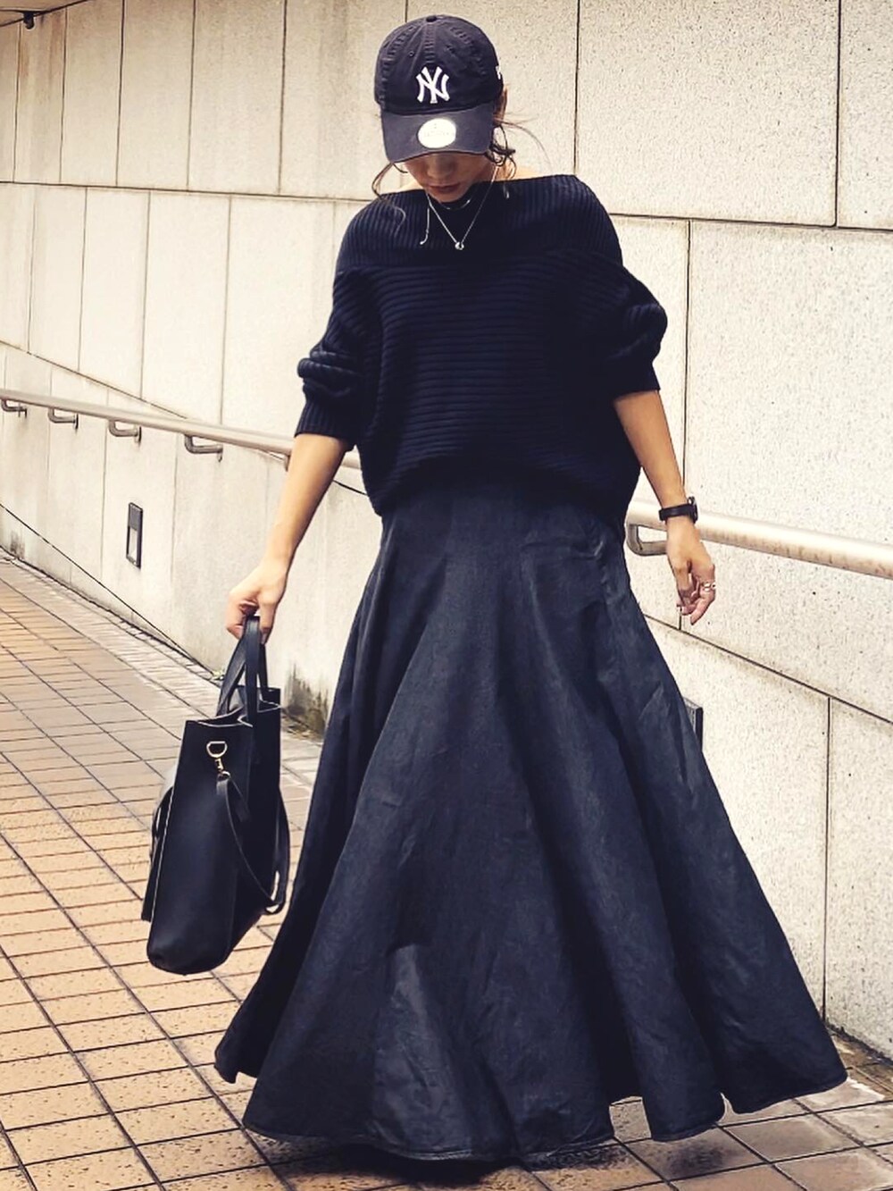 ブラック系のデニムスカート、ホワイト系のキャップ、ブラック系のアナログ腕時計を着用したレディースの秋コーディネートの3枚目の写真