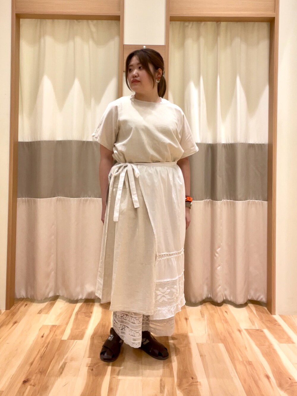 ホワイト系のワンピース、ホワイト系のパンツ、ホワイト系のエプロンを着用したレディースの春コーディネートの2枚目の写真