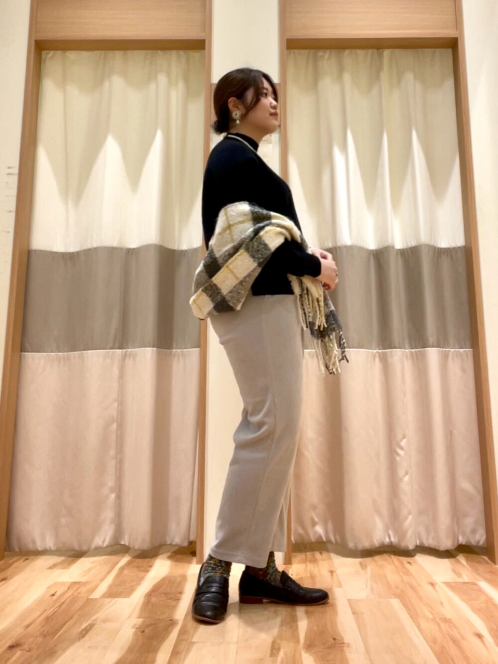 グレー系のその他パンツ、ブラック系のニット/セーター、ホワイト系のストール/ショールを着用したレディースの秋コーディネートの2枚目の写真