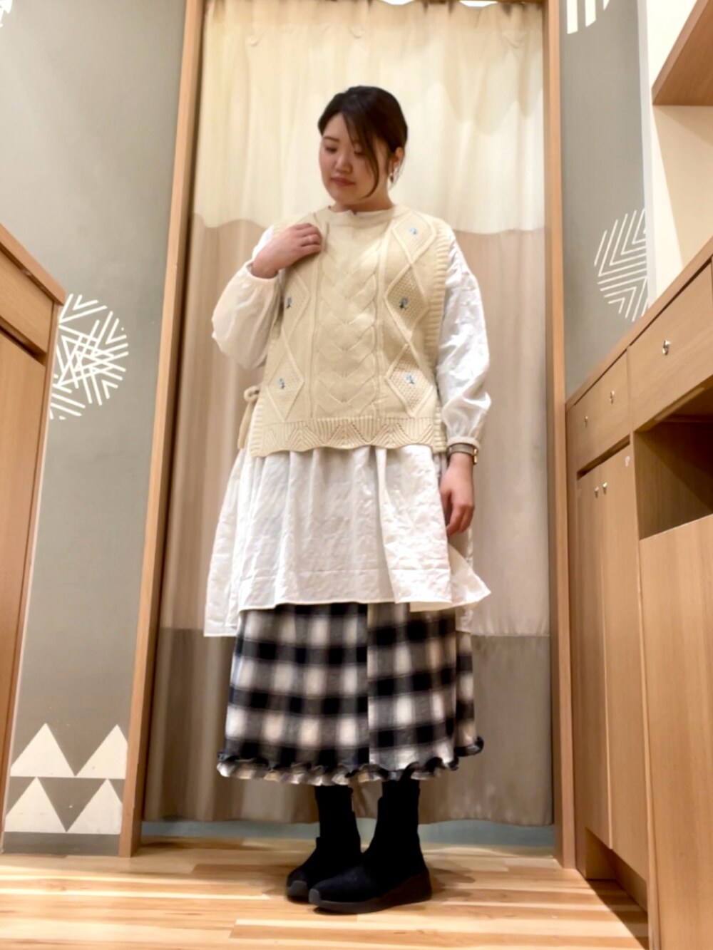 ホワイト系のチュニック、ブラック系のスカート、ベージュ系のベストを着用したレディースの冬コーディネートの2枚目の写真