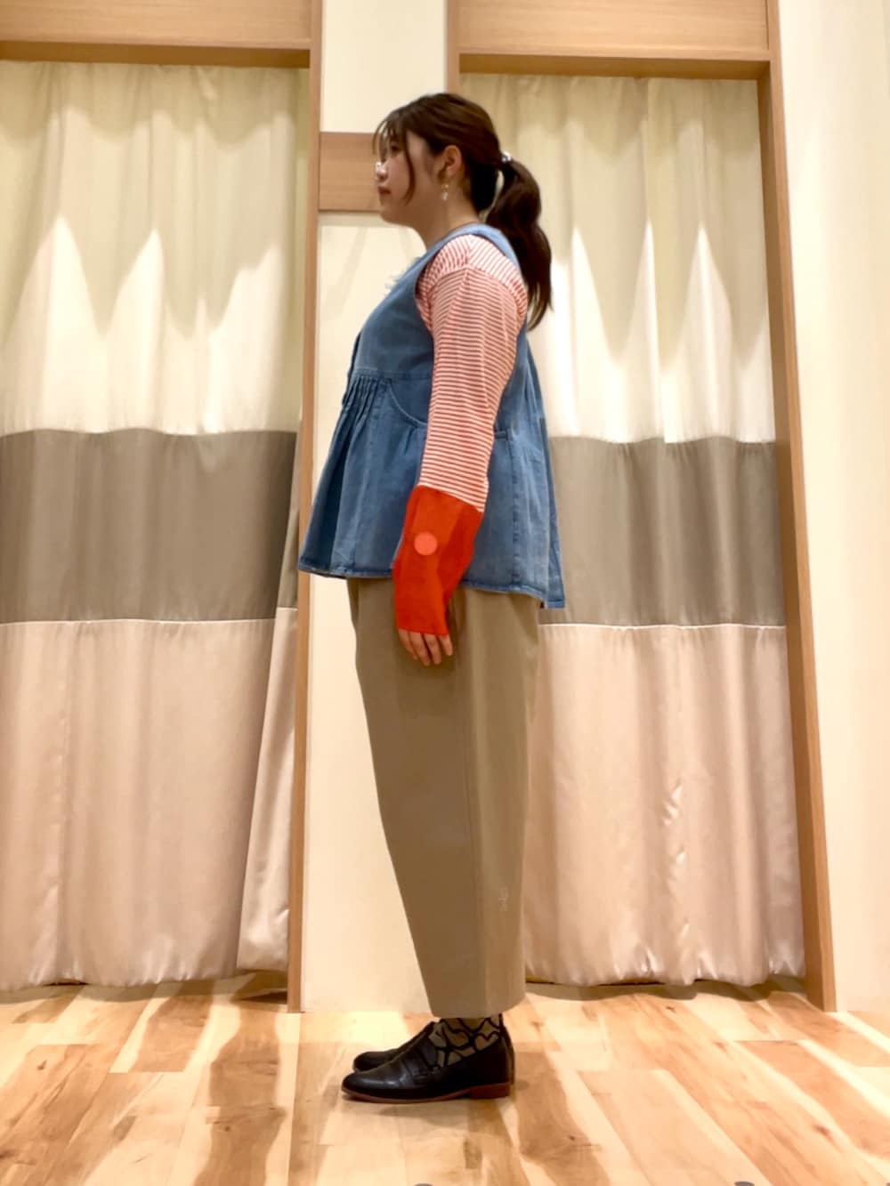 ベージュ系のその他パンツ、ブルー系のベスト、オレンジ系のTシャツ/カットソーを着用したレディースの春コーディネートの2枚目の写真