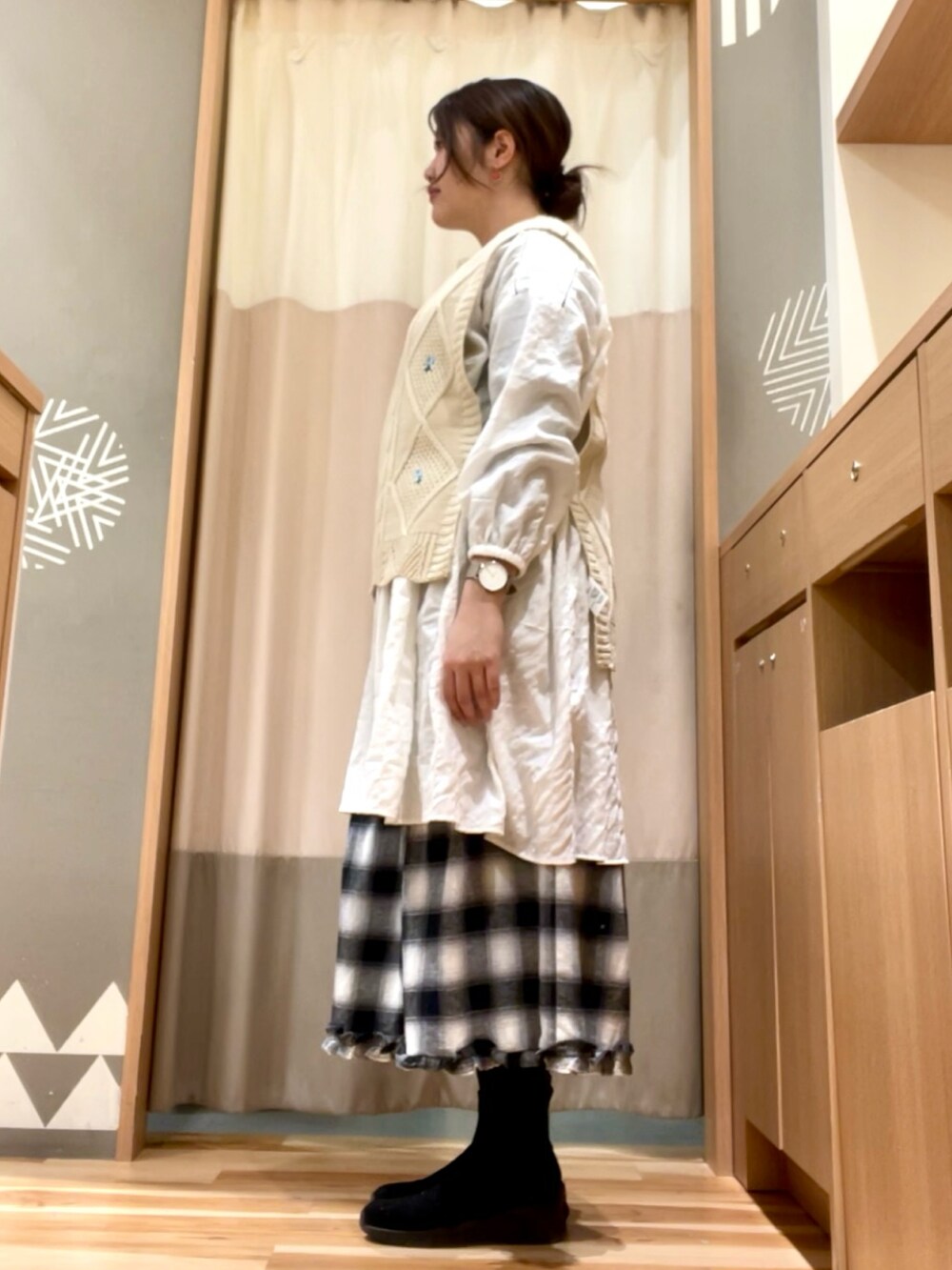 ホワイト系のチュニック、ブラック系のスカート、ベージュ系のベストを着用したレディースの冬コーディネートの3枚目の写真