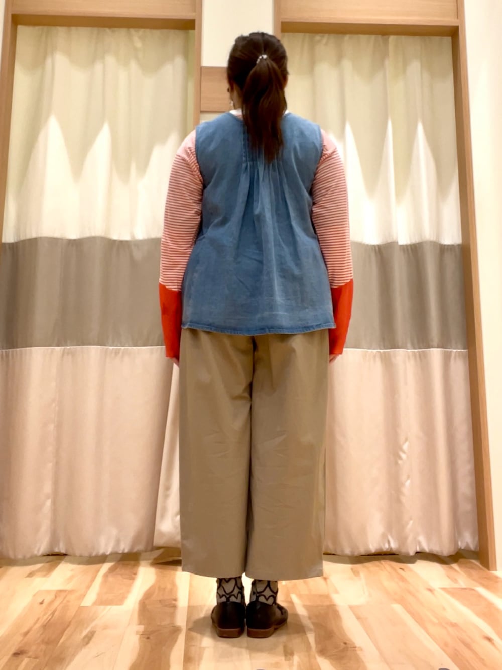 ベージュ系のその他パンツ、ブルー系のベスト、オレンジ系のTシャツ/カットソーを着用したレディースの春コーディネートの3枚目の写真