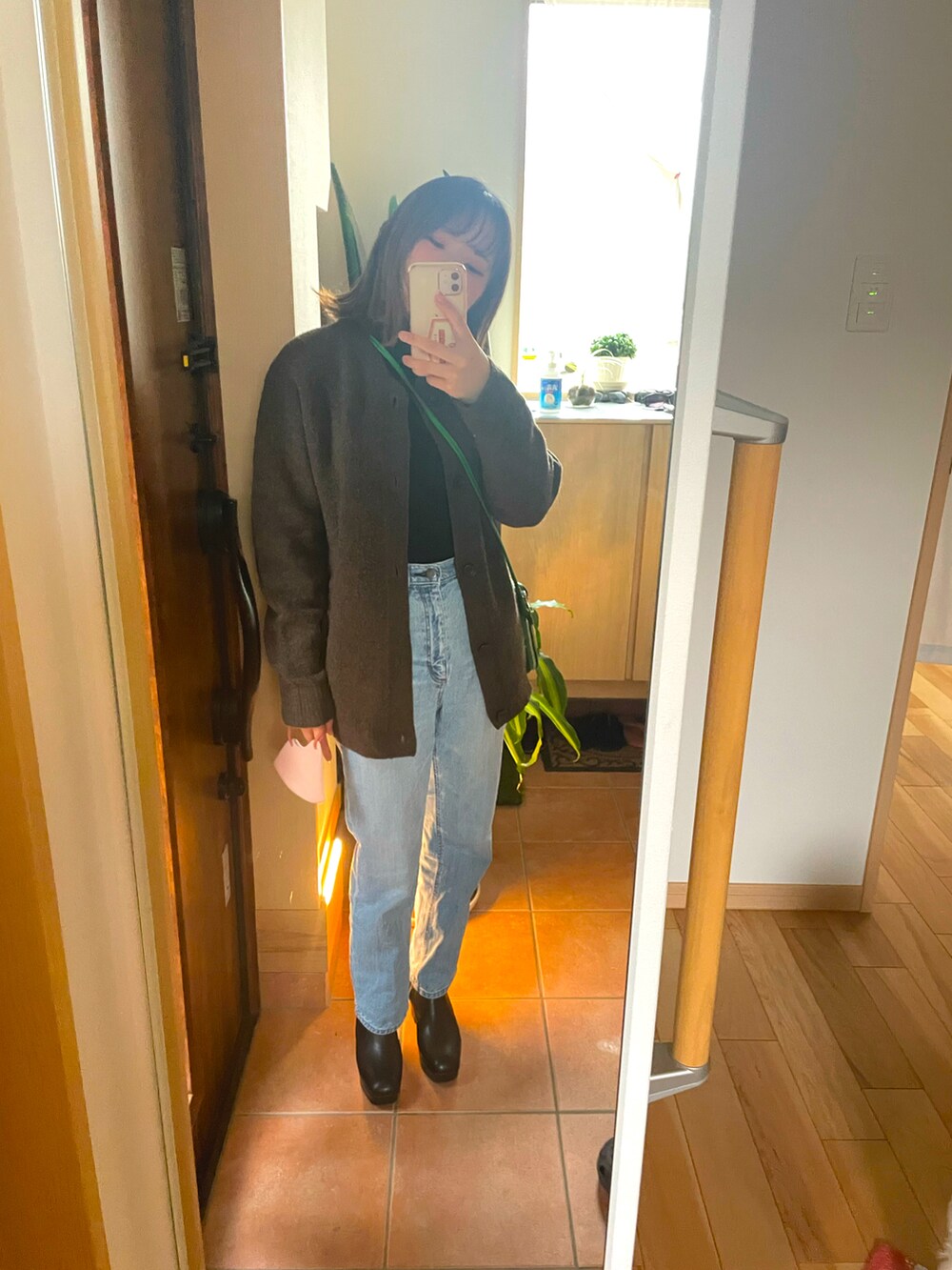 ブラウン系のカーディガン/ボレロ、ブルー系のデニムパンツ、ブラック系のブーツを着用したレディースの秋コーディネートの2枚目の写真