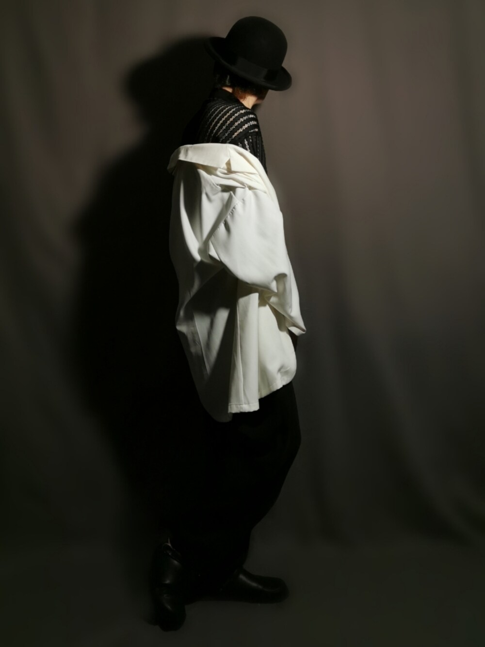 ホワイト系のテーラードジャケット、ブラック系のシャツ/ブラウス、ブラック系のスリッポンを着用したメンズの秋コーディネートの5枚目の写真