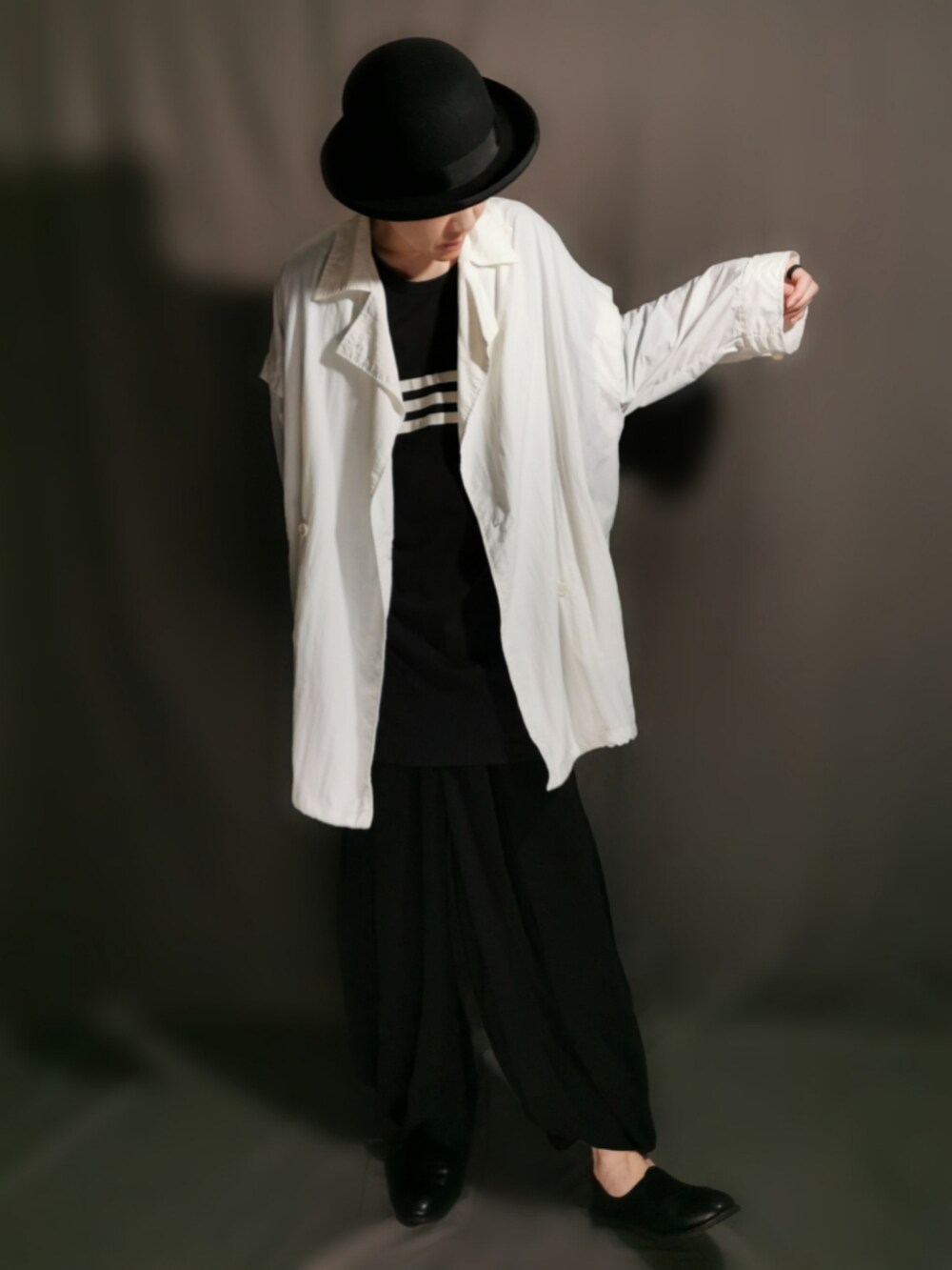 ブラック系のショルダーバッグ、ホワイト系のトレンチコート、ブラック系のサンダルを着用したメンズの秋コーディネートの4枚目の写真