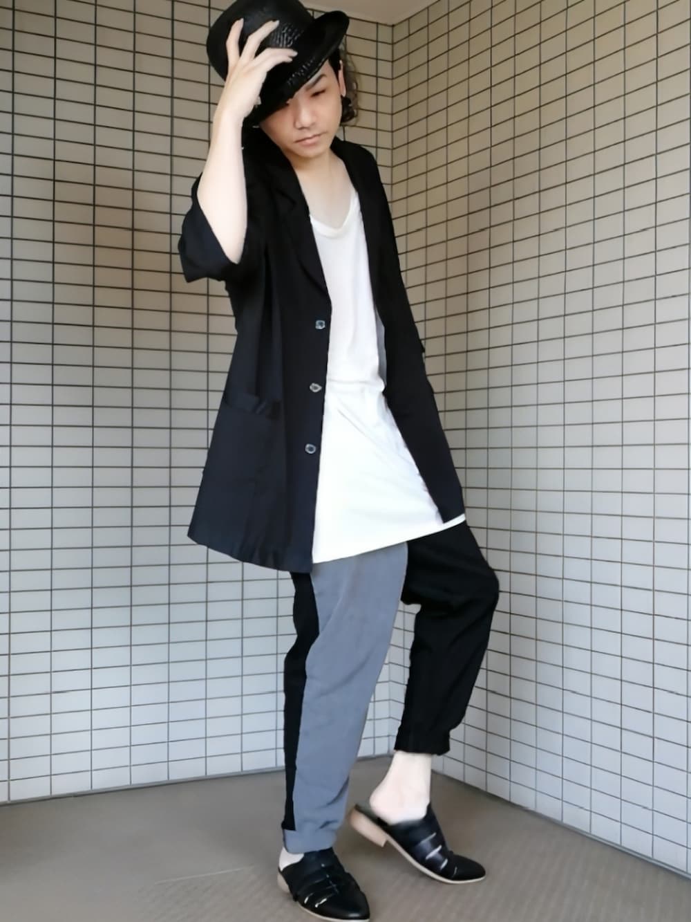 グレー系のパンツ、ブラック系のサンダル、ブラック系のテーラードジャケットを着用したメンズの夏コーディネートの2枚目の写真