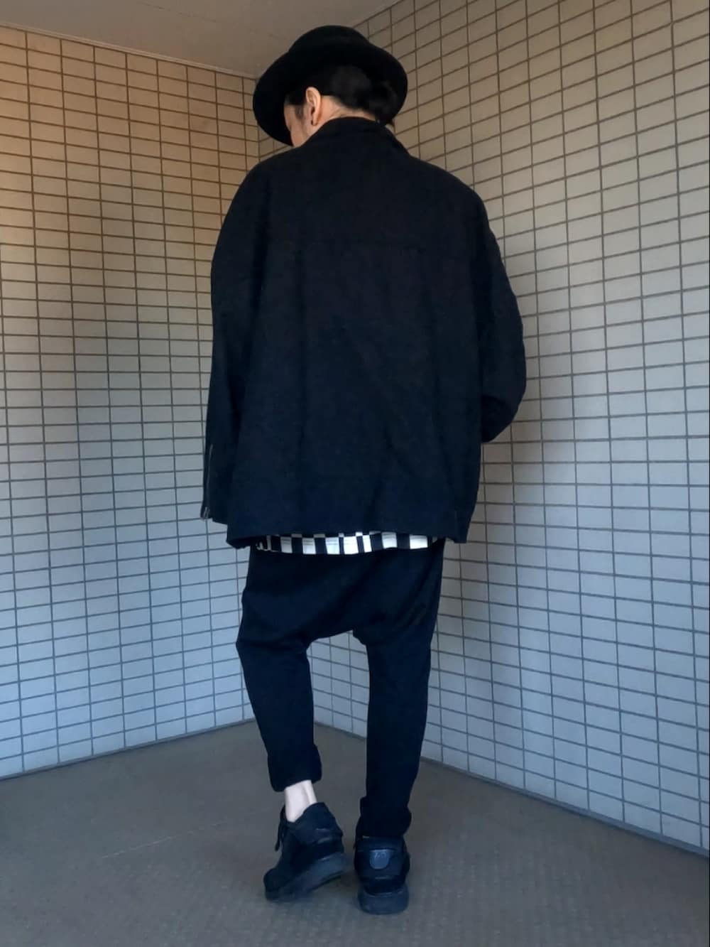 ブラック系のライダースジャケット、ブラック系のスニーカー、ブラック系のクラッチバッグを着用したメンズの冬コーディネートの4枚目の写真