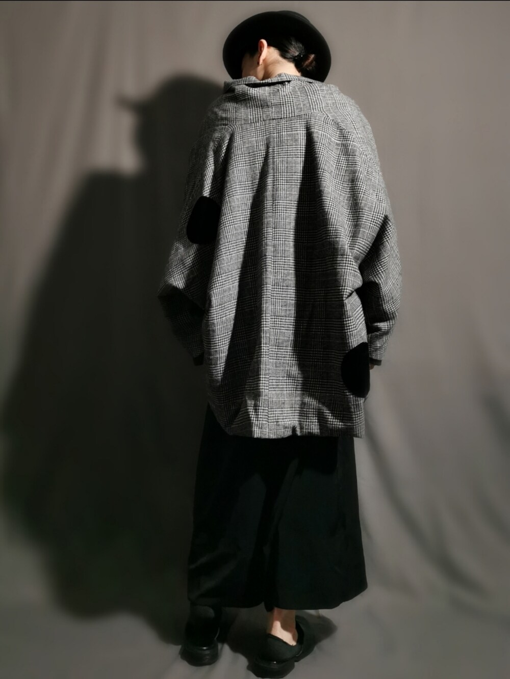 グレー系のポンチョ、ブラック系のサンダル、ブラック系のスカートを着用したメンズの冬コーディネートの4枚目の写真