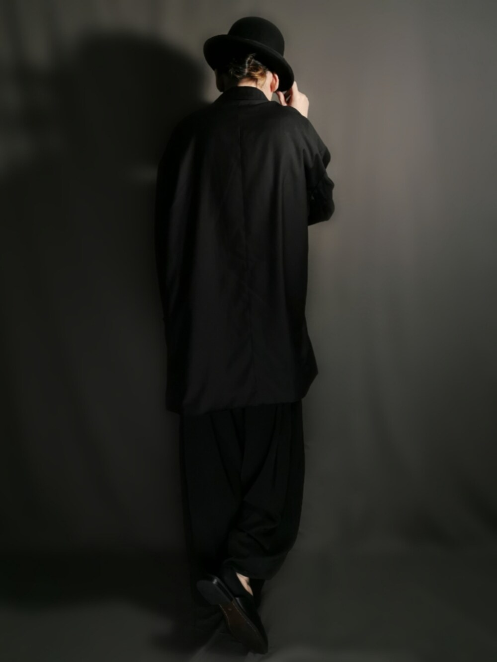 ブラック系のテーラードジャケット、ブラック系のシャツ/ブラウス、ブラック系のスカートを着用したメンズの秋コーディネートの5枚目の写真