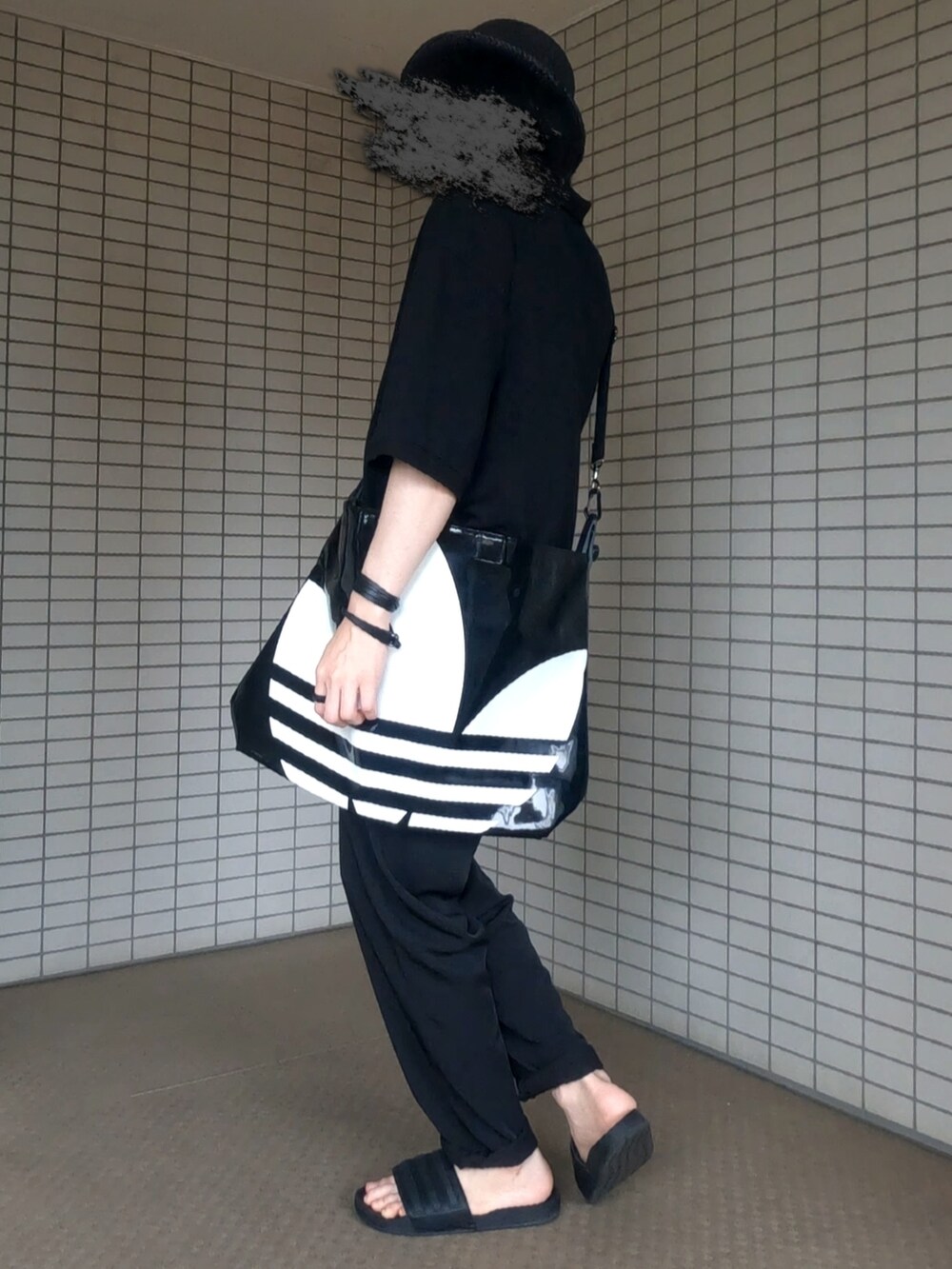 ブラック系のポロシャツ、ブラック系のトートバッグ、ブラック系のパンツを着用したメンズの夏コーディネートの2枚目の写真