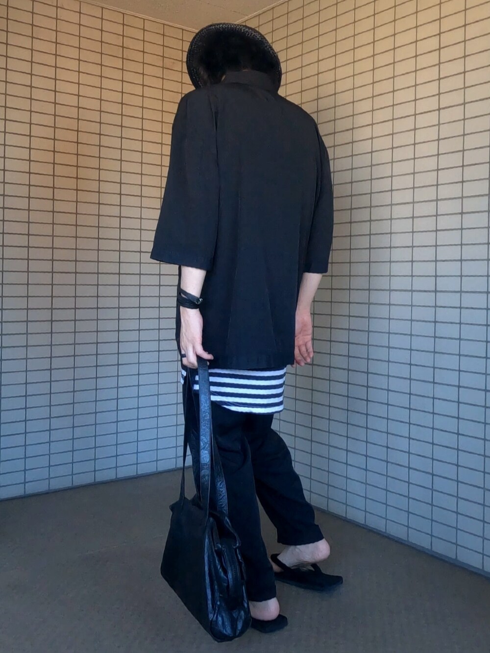 ブラック系のテーラードジャケット、ホワイト系のタンクトップ、ブラック系のパンツを着用したメンズの夏コーディネートの3枚目の写真