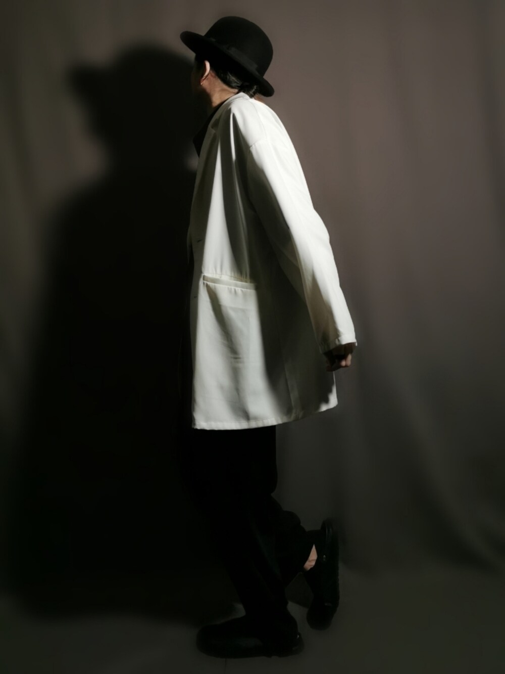 ホワイト系のテーラードジャケット、ブラック系のシャツ/ブラウス、ブラック系のスリッポンを着用したメンズの秋コーディネートの2枚目の写真