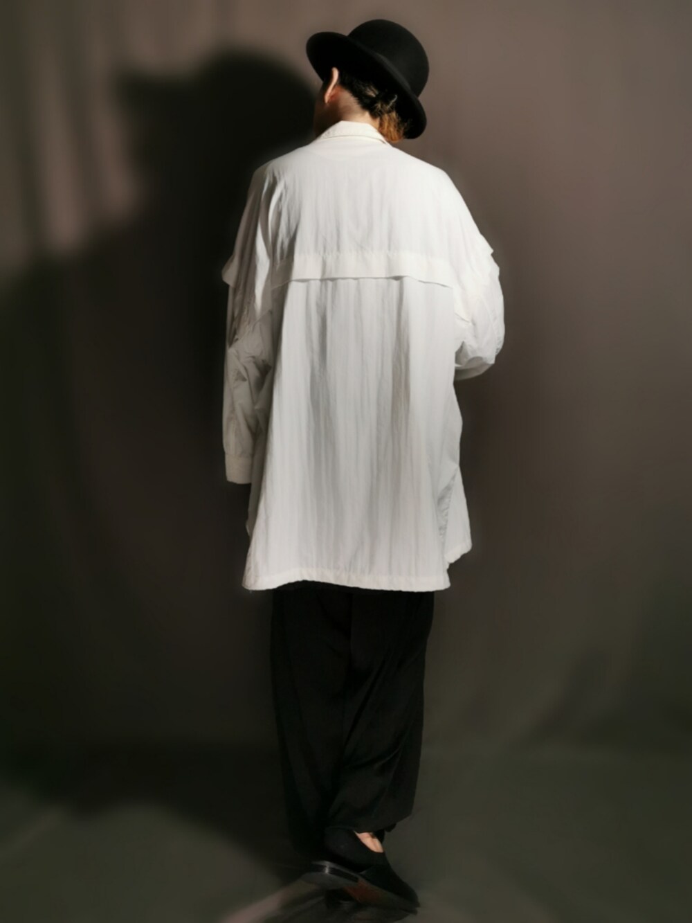 ブラック系のショルダーバッグ、ホワイト系のトレンチコート、ブラック系のサンダルを着用したメンズの秋コーディネートの5枚目の写真