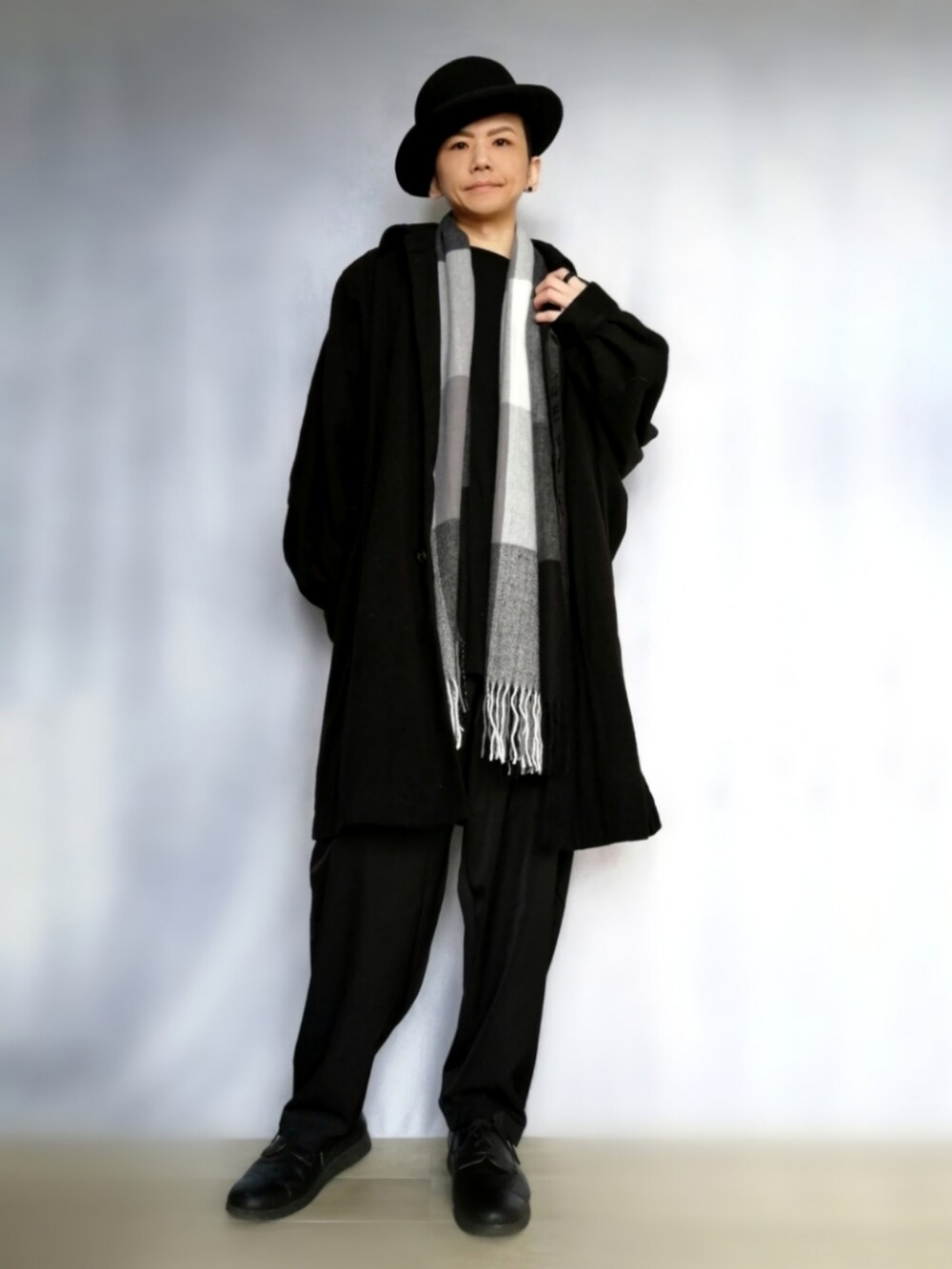 ブラック系のパンツ、ブラック系のドレスシューズ、ブラック系のステンカラーコートを着用したメンズの秋コーディネートの2枚目の写真