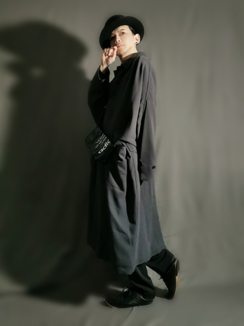 グレー系のステンカラーコート、ブラック系のショルダーバッグ、ブラック系のドレスシューズを着用したメンズの冬コーディネートの3枚目の写真